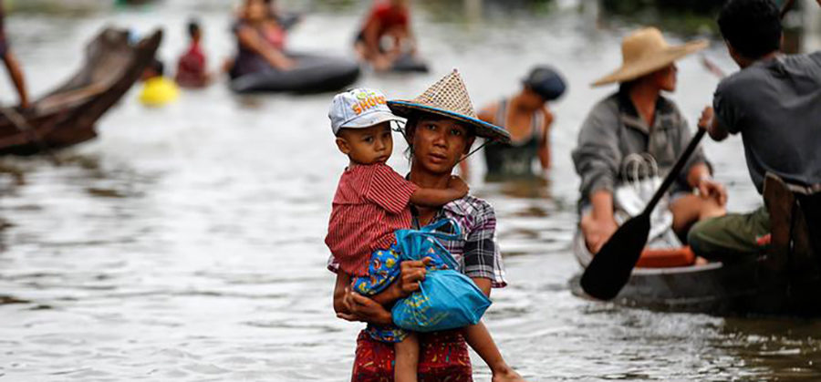 A woman carries her child as she walks through a flooded road in Kyaung Kone in Irrawaddy Region, Myanmar, August 12, 2016. / Soe Zayar Tun / Reuters