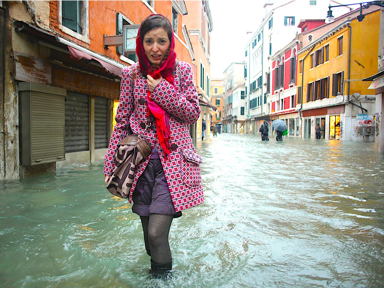 A woman walks in a flooded street during a period of seasonal high water in Venice, Italy, November 11, 2012. The water level in the canal city rose to 149 cm (59 inches) above normal. REUTERS/Manuel Silvestri